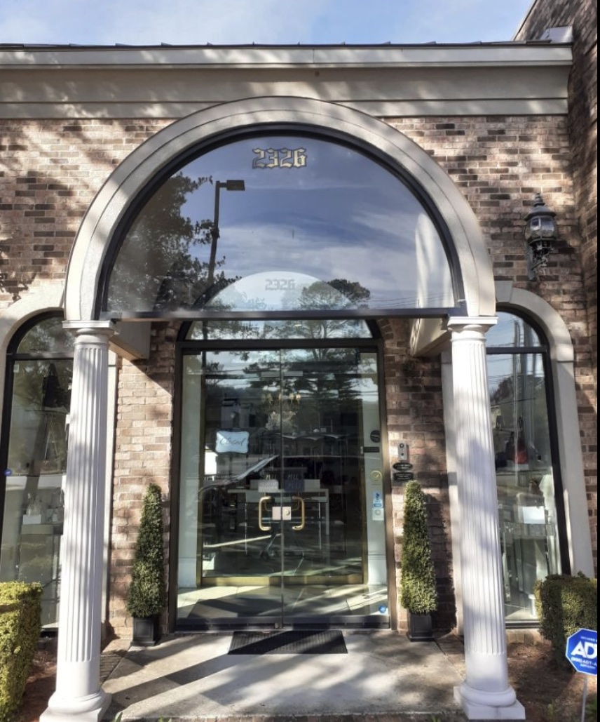 Cast stucco arch with a keystone and fluted columns framing a brick storefront entrance