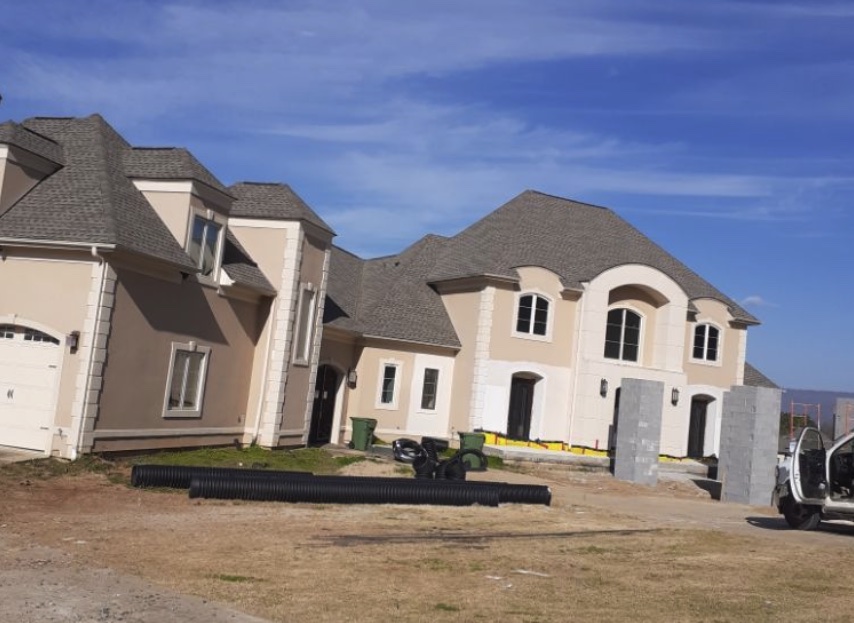 Large new-construction home with cream stucco, quoins, banding and arched window heads