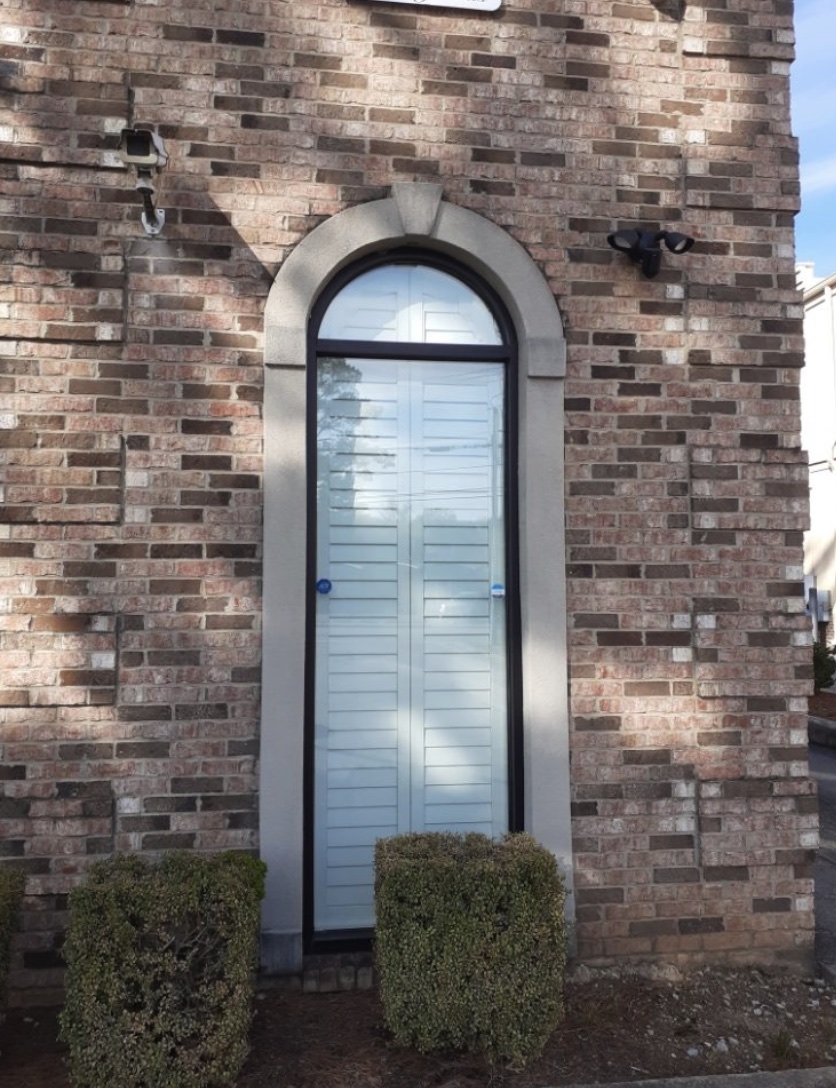 Arched stucco window surround with a keystone set into a brick wall